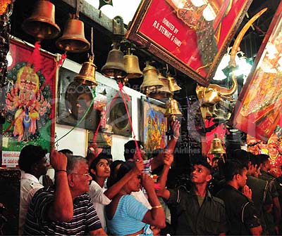 Devotees reach up to ring the bells inside Ruhunu Kataragama Maha Devalaya