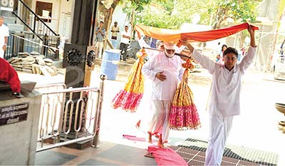All in white, the kapu mahattaya makes his ceremonial entrance to the Maha devale for the puja, his head covered in a turban and his mouth with a white cloth.